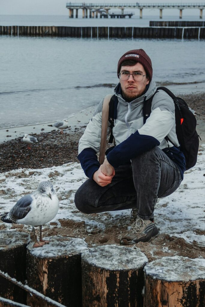 a person sitting on a dock with a bird on the shoulder